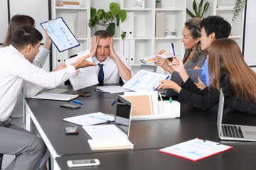 Mature businessman suffering from noisy colleagues in office