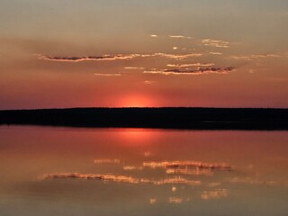 Quiet evening over the lake. Bright sunset and reflection of clouds on the surface of the water. Spring .