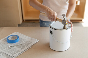 Woman closing can of paint. Using a hammer to close paint can