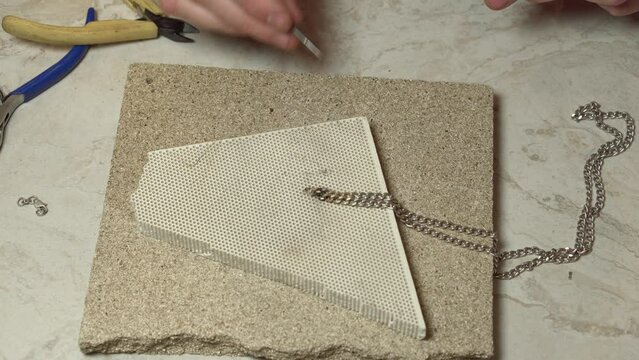 Jeweler, goldsmith behind a desk solder product. Repair silver chain.