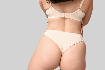 Body positive young woman in underwear on light background, back view