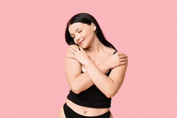 Body positive young woman in underwear on pink background