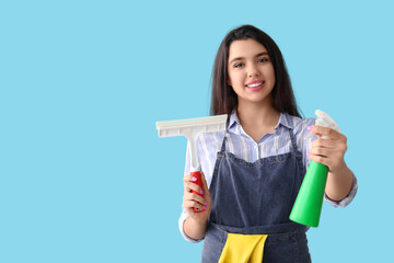 Young woman with squeegee and detergent on blue background