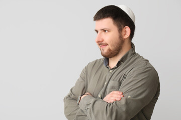 Young Jewish man in hat on light background
