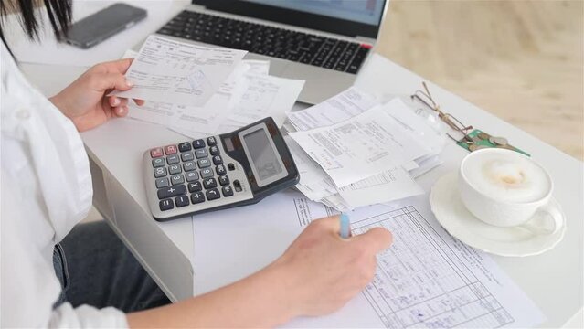 Woman hands working with financial papers on white office desk with laptop, counting on calculator, paying bills, planning budget to save some money. Independent accounting, remote accountant