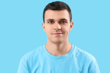 Young man with hair loss problem and marked head on blue background, closeup