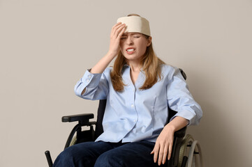 Young woman with brain concussion in wheelchair on light background