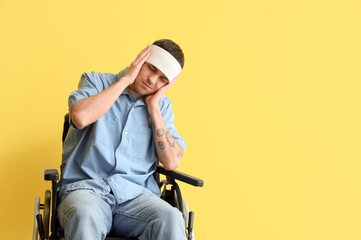 Young man with brain concussion in wheelchair on yellow background