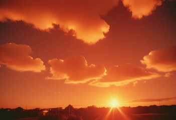 Fototapeta premium Dramatic Sunset with Sun Rays Breaking Through Clouds Over Orange and Purple Sky