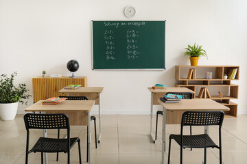 Interior of classroom with blackboard and desks