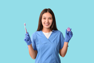 Young female dentist with toothpaste and dental floss on blue background
