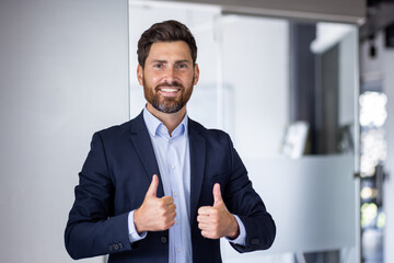 Confident business executive giving a thumbs up in modern office