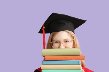 Female graduating student in mortar board with books on lilac background