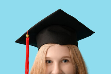 Female graduating student in mortar board on blue background, closeup