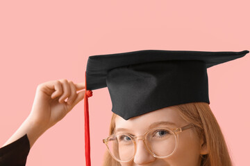 Female graduating student in mortar board on pink background, closeup
