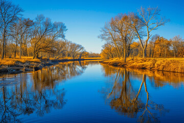Fototapeta na wymiar A tranquil image of a meandering river reflecting the clear blue sky, with trees lining its banks and creating a serene, natural setting.