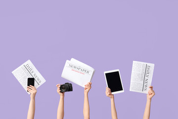 Female hands with newspapers and modern gadgets on lilac background
