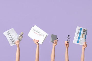 Female hands with newspapers, microphone and notebook on lilac background
