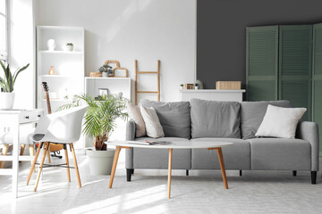 Interior of light living room with green plants and sofa