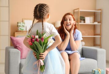 Little girl greeting her mom with Mother's Day in living room
