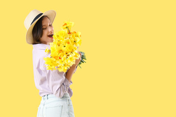 Young woman in hat with daffodils on yellow background
