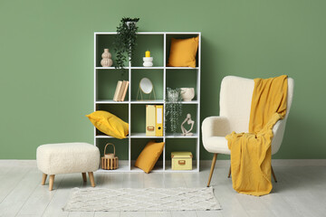 Interior of living room with comfortable armchair, shelving unit and plaid