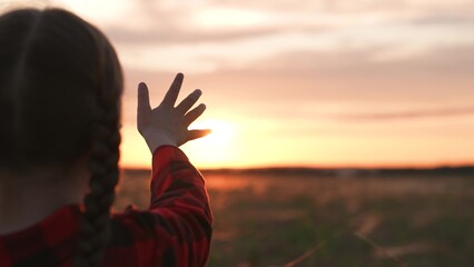 Girl dreamily reaches for sun with hand. Symbolism striving for light wisdom spiritual enlightenment knowledge self-development aspirations. Expectation of miracle dreams inspiration of young child.