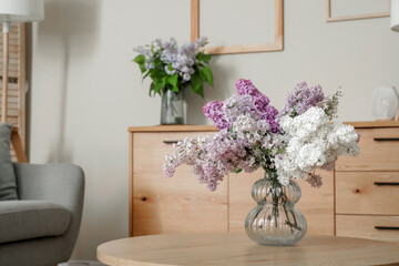 Table with beautiful flowers and chest of drawers in interior of stylish living room