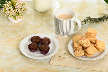 breakfast table, a cup of coffee with milk and cookies on a saucer
