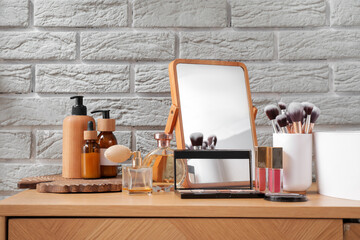 Set of decorative cosmetics, bottles of cosmetic products, brushes in holder and sink near white...