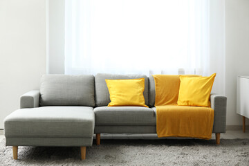 Interior of living room with comfortable sofa, cushions and yellow plaid