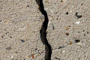 A crack in the pavement with rocks and debris in it