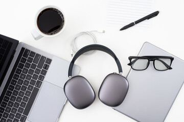 Clean minimalist flat lay birds eye view of office desk with headphones, coffee, laptop, tablet,...