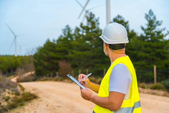 Engineer inspecting wind turbines in a green energy park