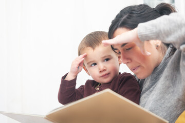 A woman and a child are sitting together and looking at a book