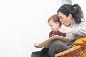 A woman and a baby are sitting together and reading a book