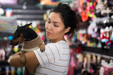 Portrait of happy woman with his dog in winter clothes visiting pet supplies shop