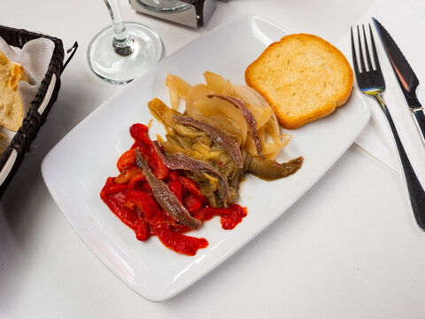 Festive and everyday vegetable dish of Catalan cuisine is escalibada. Large pieces of eggplant, pepper, onion baked in oven, complemented with salted anchovies and toasts.