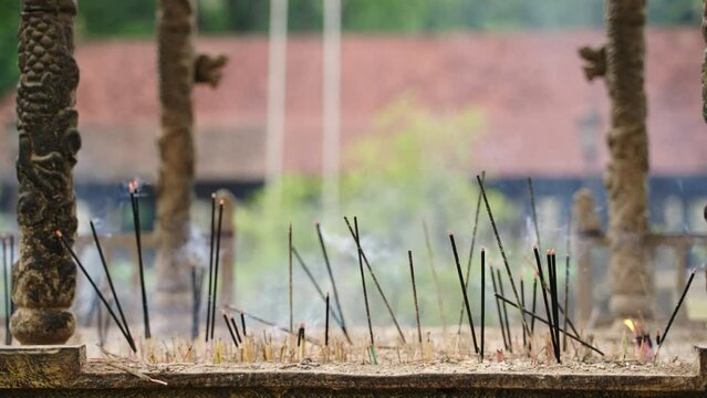 Incense sticks burn amidst ancient temple pillars, smoke fills air. Traditional Buddhist ritual in sacred place. Meditation, spiritual atmosphere, worship in Kandy, Sri Dalada Maligawa.