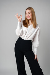 Young Woman Gesturing OK Sign With Hand Against a Neutral Background