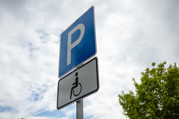 Parking sign for people with a disability. Summer day, clouds, blue sky, nobody. 
