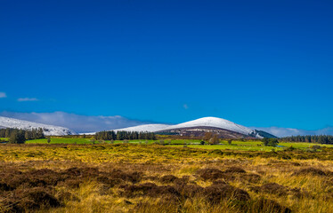 Naklejka premium Snow-Capped Majesty: Djouce Mountain Standing Tall under a Clear Blue Sky