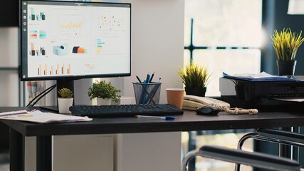 Wheelchair in inclusive office and display showing marketing planning data. Medical chair in workspace offering accessibility to workers with disability and monitor with business analytics