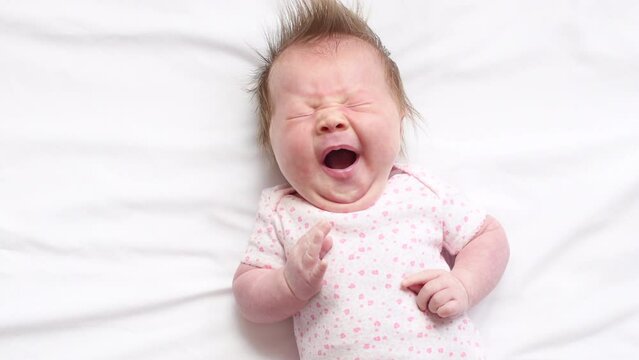 4K video of Cute Caucasian newborn baby girl yawning at the white background 