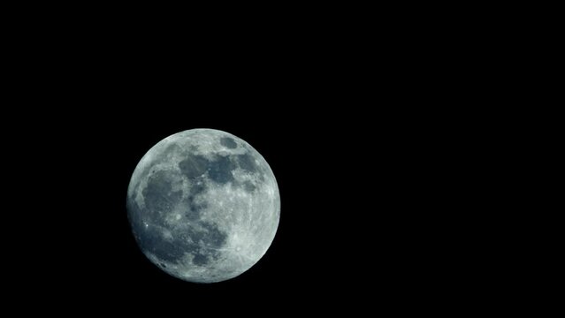A large full moon moves slowly across the night sky. Its surface, pockmarked with craters and scars, is a testament to the aeons it has presided over the earth below.