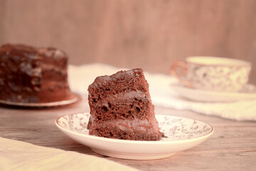 Slice of Little Chocolate Cake with Chocolate Ganache on a Plate with Tea. Tea Time