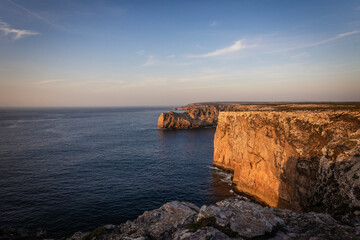 Landscape photo of dramatic, steep orange cliffs by the atlantic at sunset. Shot in Farol fo Cabo...