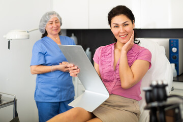 Smiling female patient satisfied after cosmetological procedure in esthetic clinic