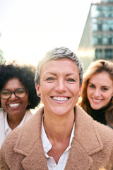 Vertical. Portrait group empowered business women of diverse ages looking smiling at camera with...