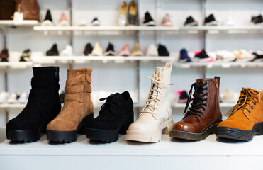 Closeup of leather and suede womens ankle boots displayed on shelves in shoe boutique.